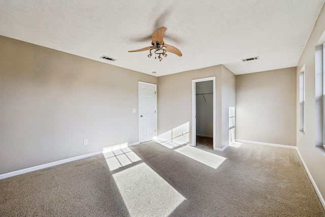 unfurnished bedroom featuring carpet, a textured ceiling, visible vents, and baseboards