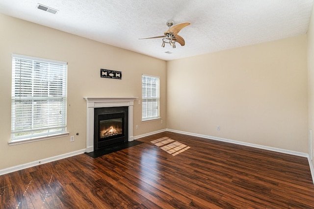 unfurnished living room featuring hardwood / wood-style floors, a fireplace with flush hearth, visible vents, and a healthy amount of sunlight