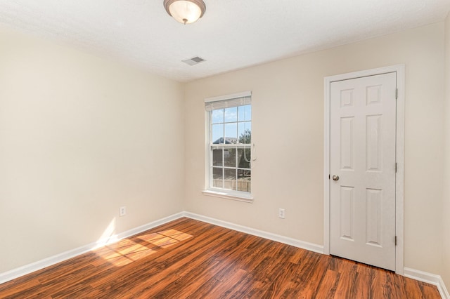 unfurnished room featuring wood finished floors, visible vents, and baseboards