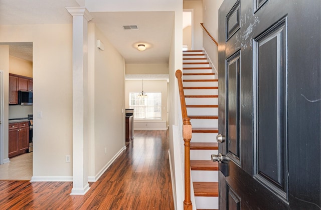 foyer featuring dark wood-style flooring, decorative columns, visible vents, stairway, and baseboards