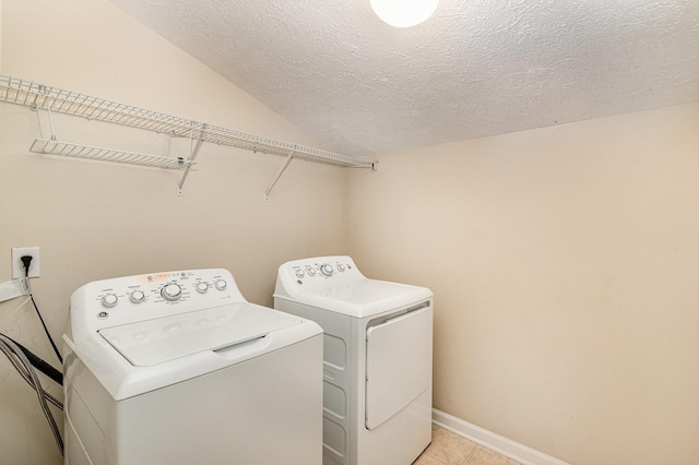 laundry area with laundry area, baseboards, a textured ceiling, washing machine and dryer, and light tile patterned flooring