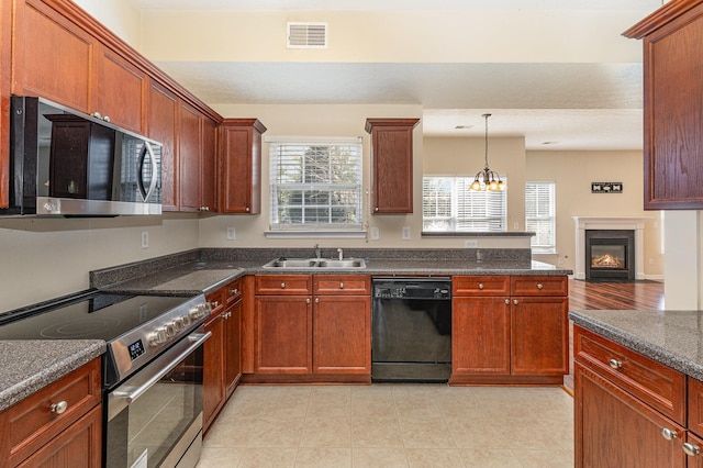 kitchen with a fireplace with flush hearth, a sink, visible vents, appliances with stainless steel finishes, and pendant lighting