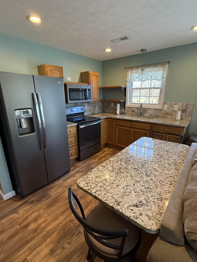 kitchen featuring dark wood-style floors, visible vents, backsplash, appliances with stainless steel finishes, and a sink