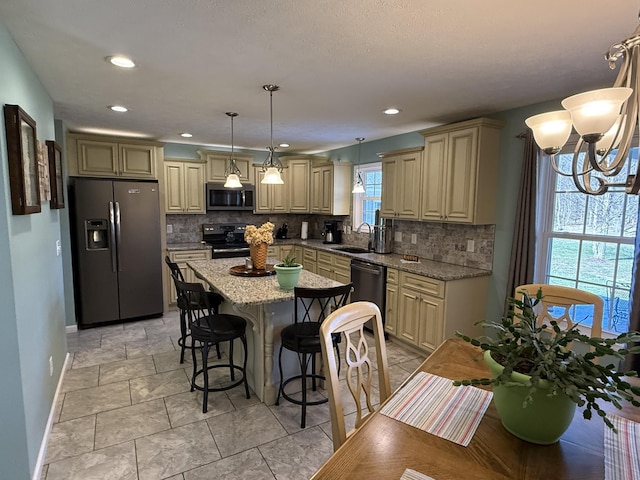 kitchen featuring stainless steel appliances, cream cabinets, a sink, and a center island