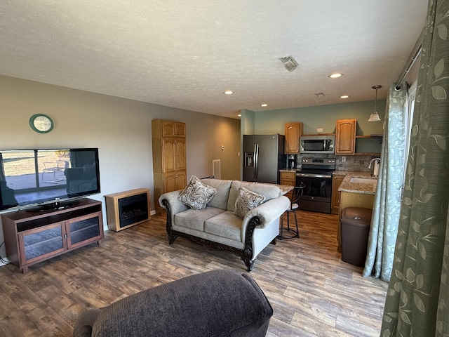 living room featuring a textured ceiling, wood finished floors, and recessed lighting