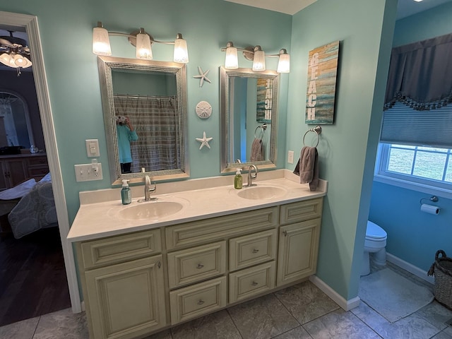 bathroom featuring double vanity, a sink, toilet, and baseboards