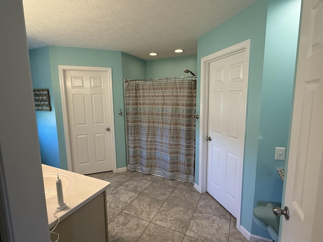 bathroom featuring baseboards, a shower with shower curtain, vanity, and a textured ceiling