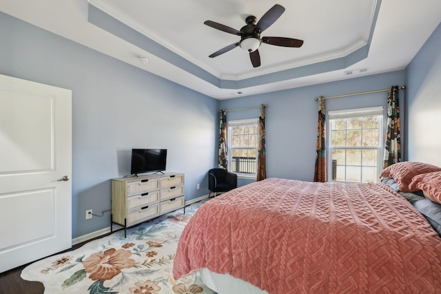 bedroom featuring a tray ceiling, multiple windows, and visible vents