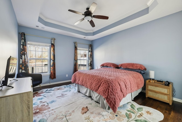 bedroom with hardwood / wood-style flooring, visible vents, baseboards, ornamental molding, and a raised ceiling