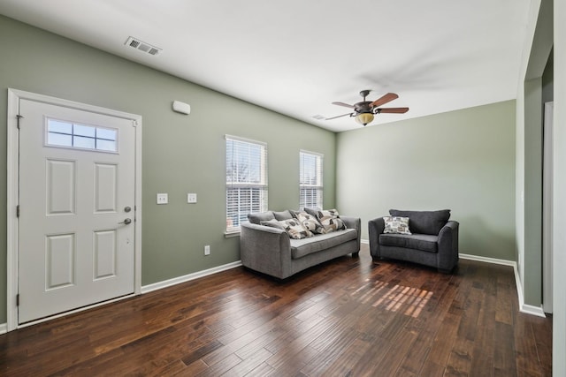 living area featuring hardwood / wood-style flooring, baseboards, visible vents, and a ceiling fan