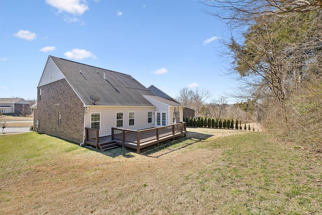 rear view of property with a shingled roof, a yard, and a wooden deck