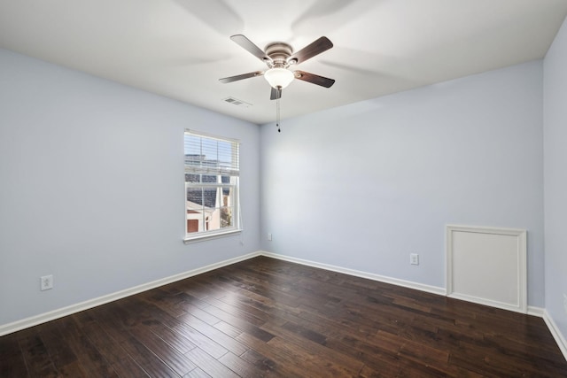 empty room with dark wood-style floors, visible vents, ceiling fan, and baseboards