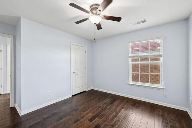 spare room with dark wood-style flooring, visible vents, ceiling fan, and baseboards