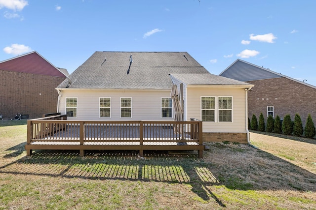 rear view of house featuring roof with shingles, a deck, and a yard