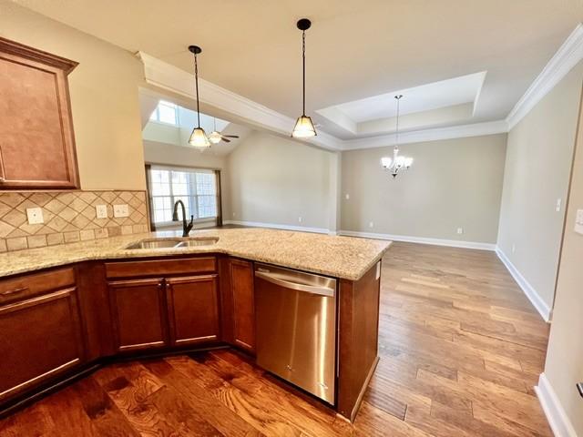 kitchen with dishwasher, dark wood-style floors, a peninsula, a tray ceiling, and a sink