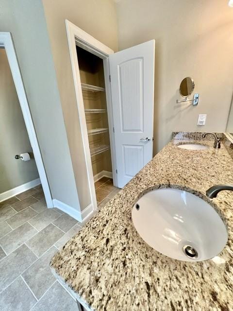 full bath with double vanity, tile patterned flooring, a sink, and baseboards