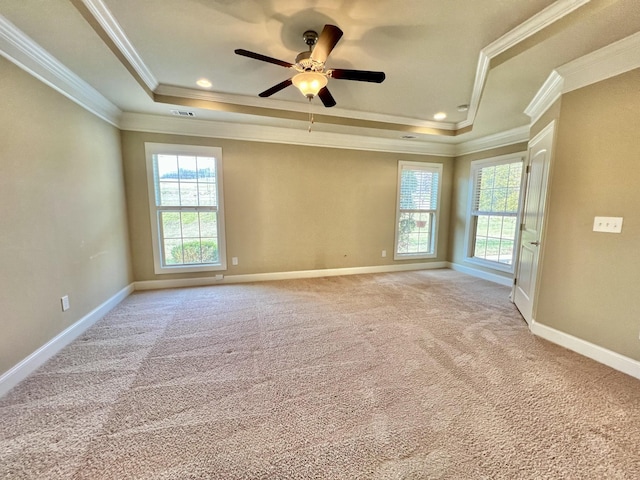 empty room with baseboards, a tray ceiling, ornamental molding, and light colored carpet