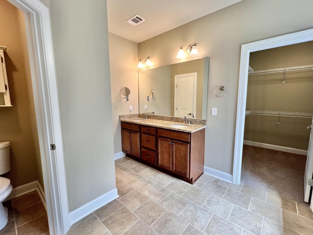 full bath with double vanity, visible vents, toilet, a sink, and baseboards