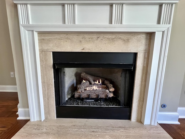 details featuring a fireplace with flush hearth, baseboards, and wood finished floors