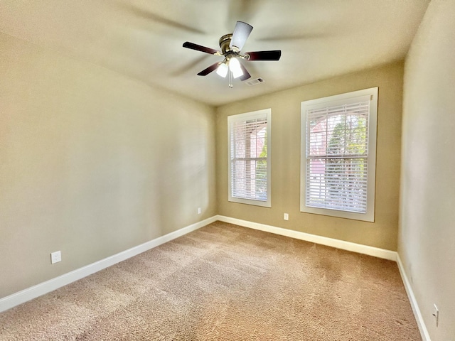 carpeted spare room with visible vents, ceiling fan, and baseboards