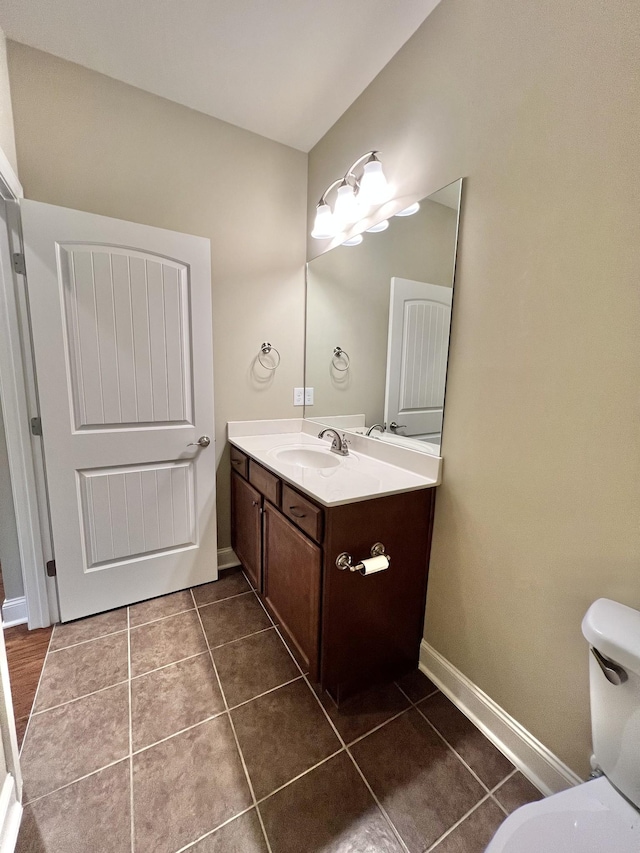 bathroom featuring toilet, tile patterned flooring, vanity, and baseboards