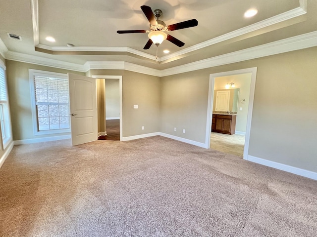 unfurnished bedroom with a tray ceiling, crown molding, visible vents, light carpet, and baseboards