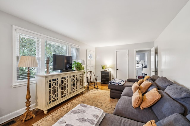 living area featuring wood finished floors, visible vents, and baseboards