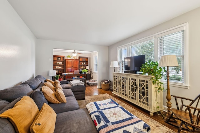 living room featuring ceiling fan, baseboards, and wood finished floors