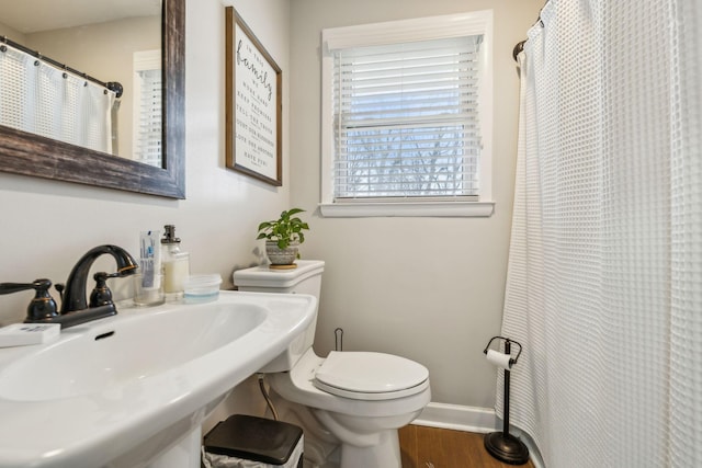 bathroom featuring a sink, wood finished floors, toilet, and baseboards