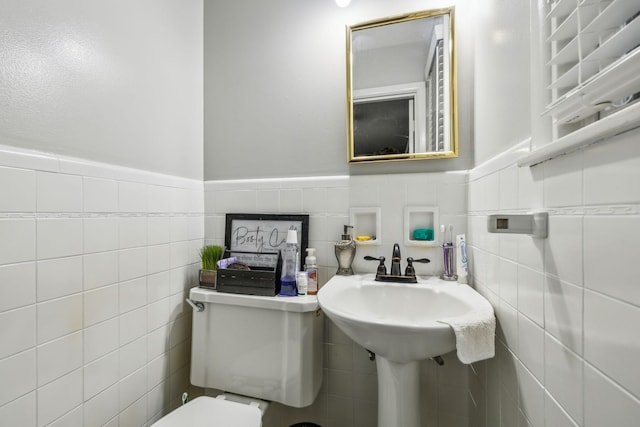 half bathroom featuring wainscoting and toilet