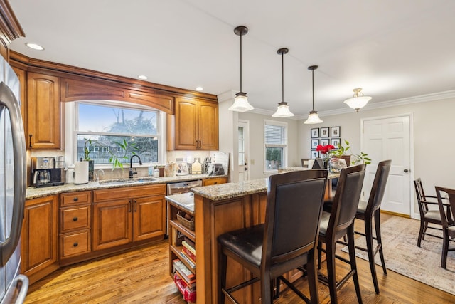 kitchen with light wood-style flooring, a kitchen island, a breakfast bar, and a sink