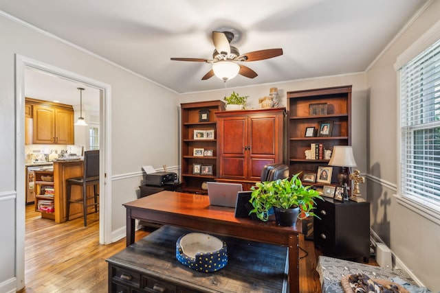 home office with light wood-type flooring, ceiling fan, baseboards, and crown molding