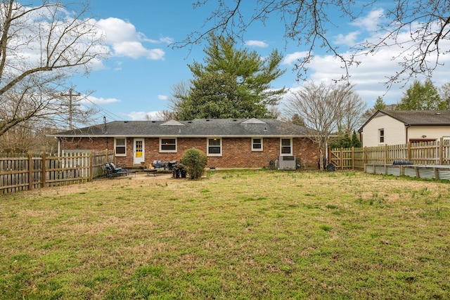 back of property featuring a yard, brick siding, and a fenced backyard