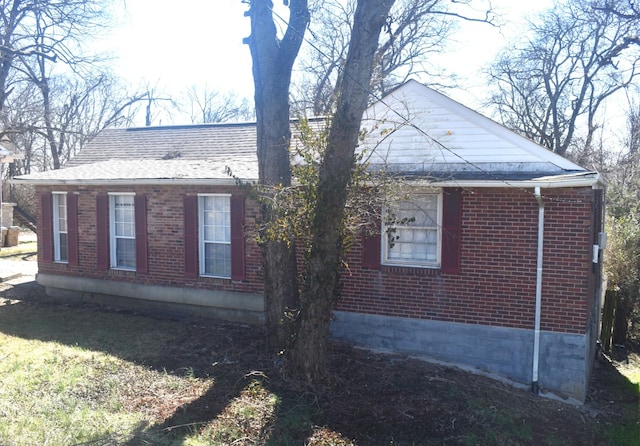 view of home's exterior with brick siding and a shingled roof