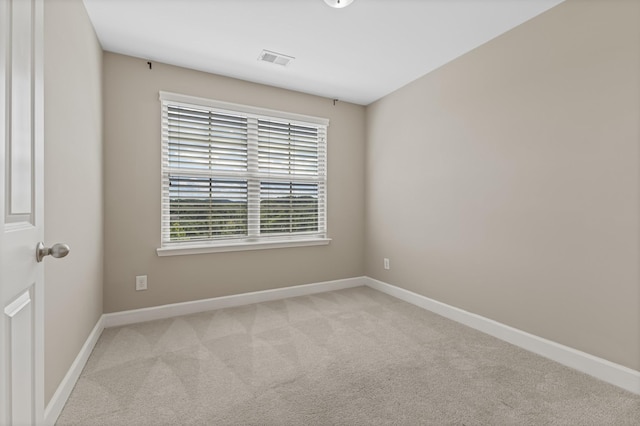 spare room featuring carpet floors, visible vents, and baseboards