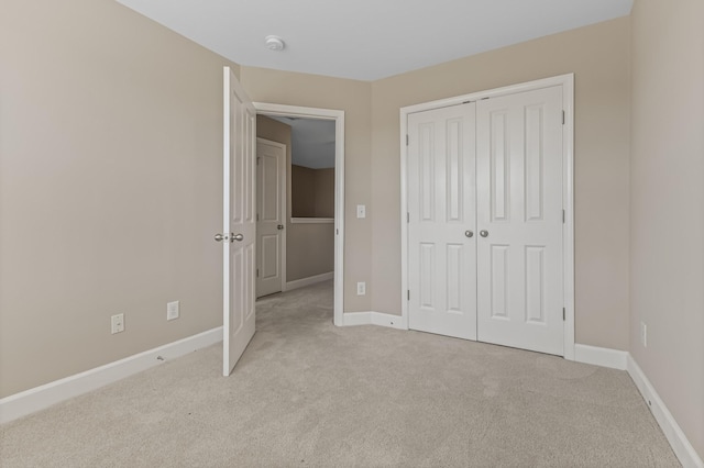 unfurnished bedroom with baseboards, a closet, and light colored carpet