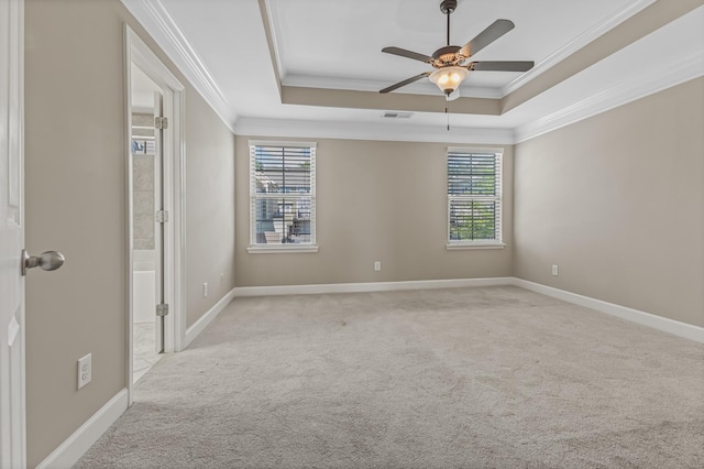 empty room with visible vents, a raised ceiling, and ornamental molding