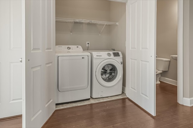 laundry area featuring laundry area, baseboards, washer and clothes dryer, and dark wood-type flooring