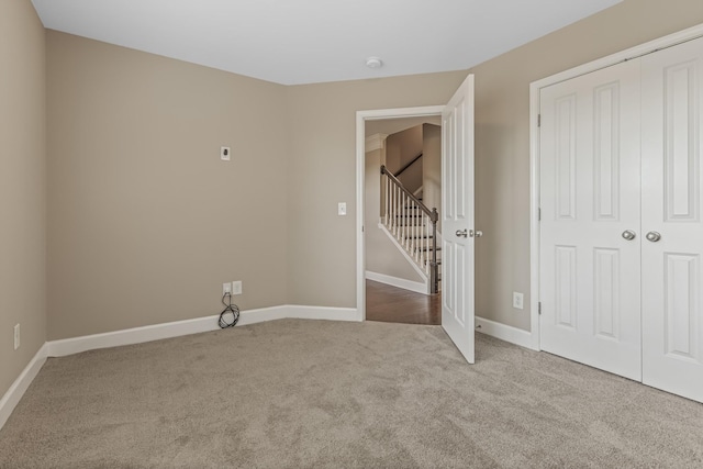 unfurnished bedroom with carpet floors, a closet, and baseboards