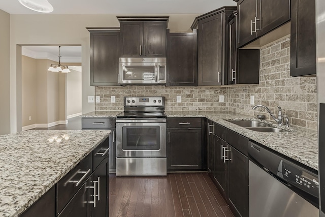 kitchen featuring a sink, appliances with stainless steel finishes, ornamental molding, decorative backsplash, and dark wood-style floors