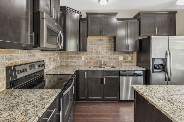 kitchen featuring tasteful backsplash, appliances with stainless steel finishes, dark wood-type flooring, a sink, and light stone countertops