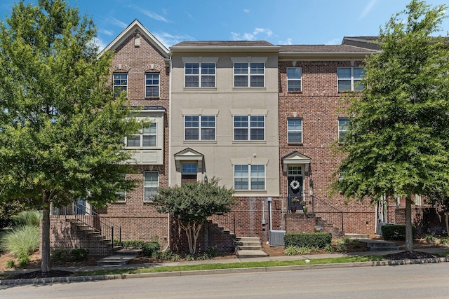 view of front of property featuring central air condition unit, brick siding, and stucco siding