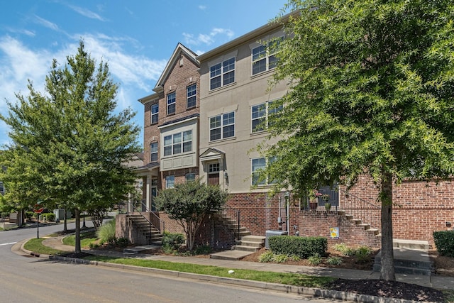 multi unit property featuring stucco siding, stairs, and brick siding