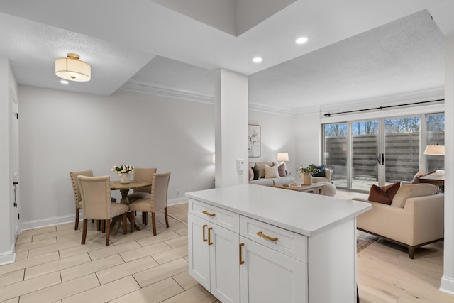 kitchen with white cabinets, open floor plan, light countertops, light wood-style floors, and recessed lighting