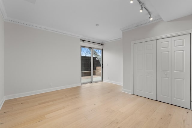 unfurnished bedroom featuring baseboards, access to exterior, crown molding, light wood-style floors, and a closet