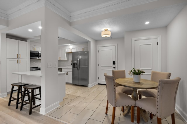 dining space featuring light wood finished floors, baseboards, and crown molding