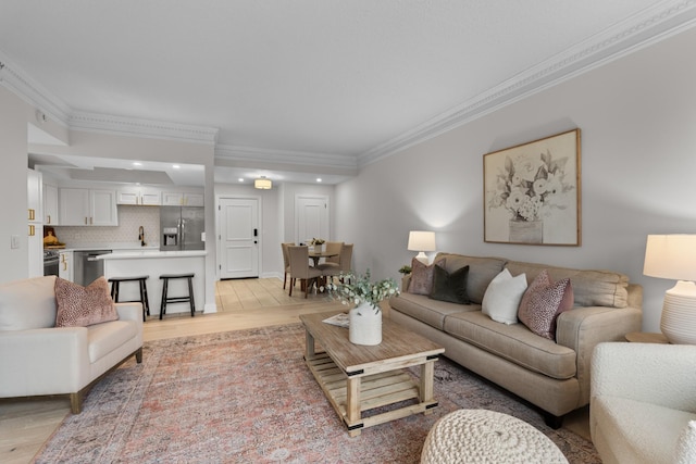 living area featuring ornamental molding, light wood-style flooring, and recessed lighting