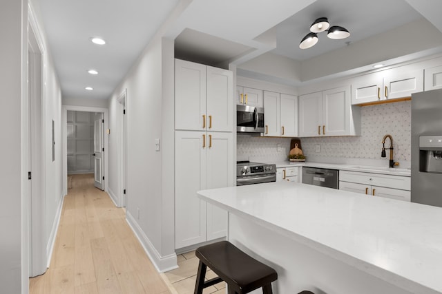 kitchen with a breakfast bar, tasteful backsplash, stainless steel appliances, and a sink