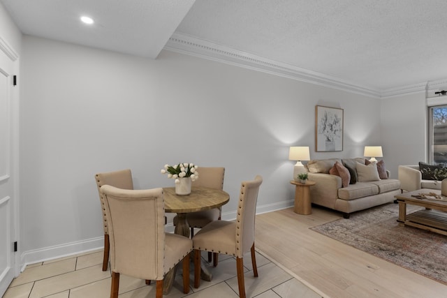 dining space featuring baseboards, a textured ceiling, crown molding, light wood-type flooring, and recessed lighting