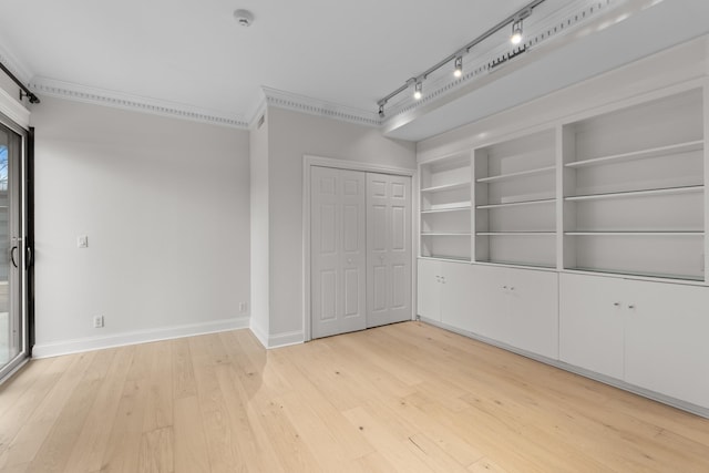 unfurnished room featuring light wood-style flooring, built in shelves, ornamental molding, and baseboards